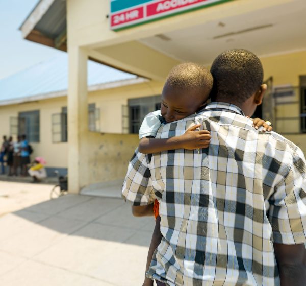 Sygeplejer bærer tre-årig dren til hospitalet i det nordlige Kenya.